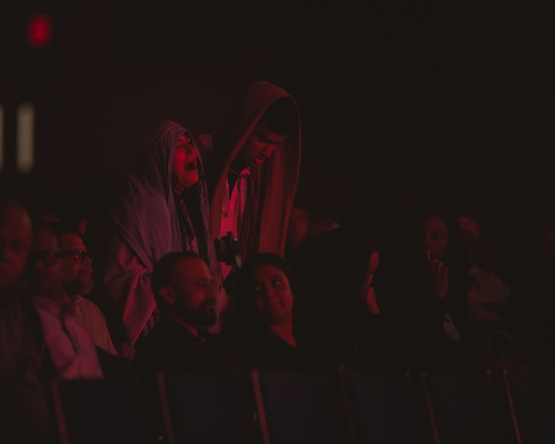 A group of people are sitting in a dark room watching a concert.