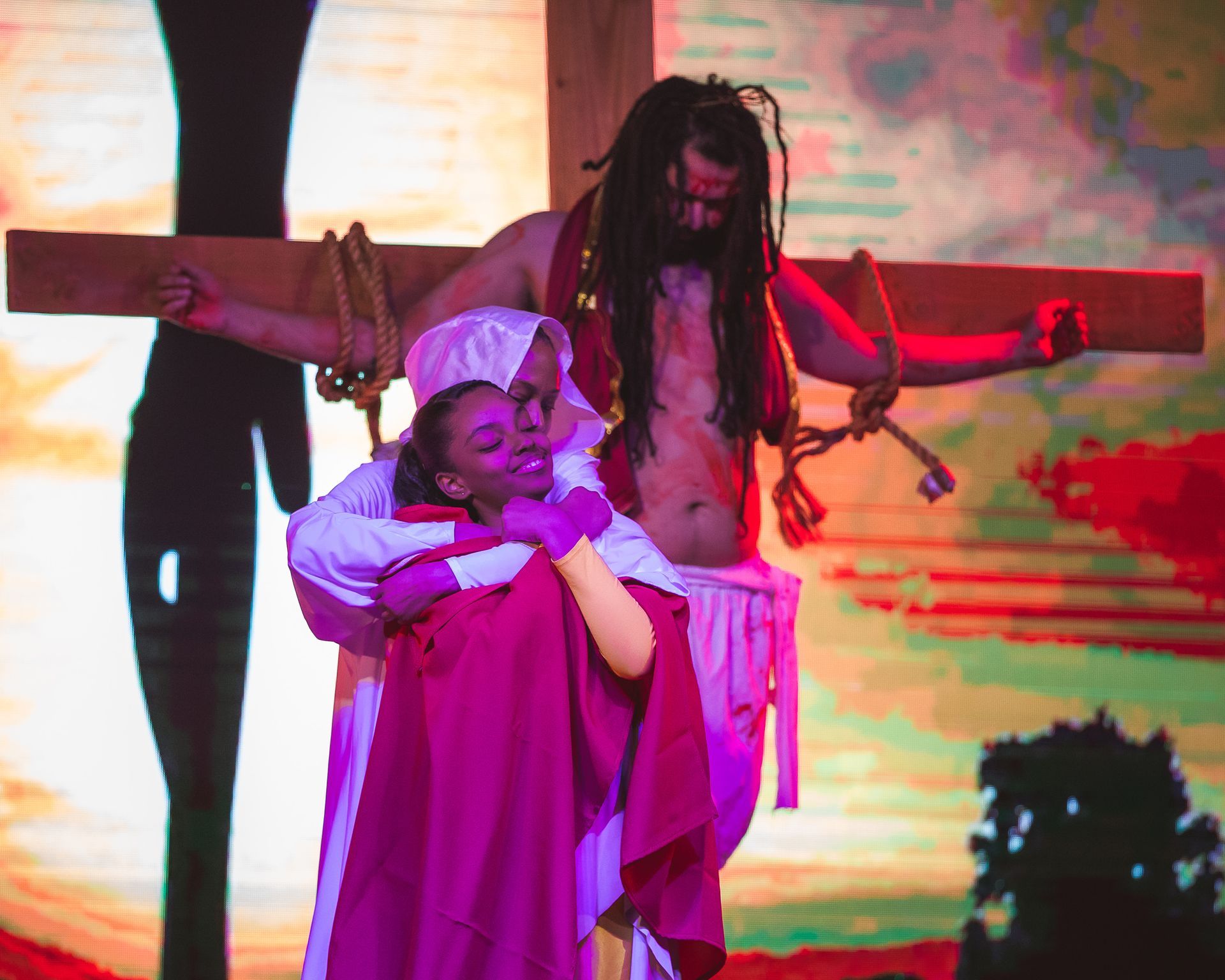 A man is hanging on a cross with a woman hugging him.