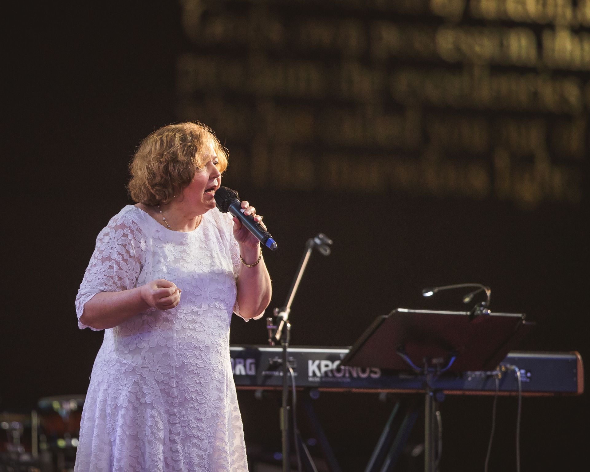 A woman in a white dress singing into a microphone