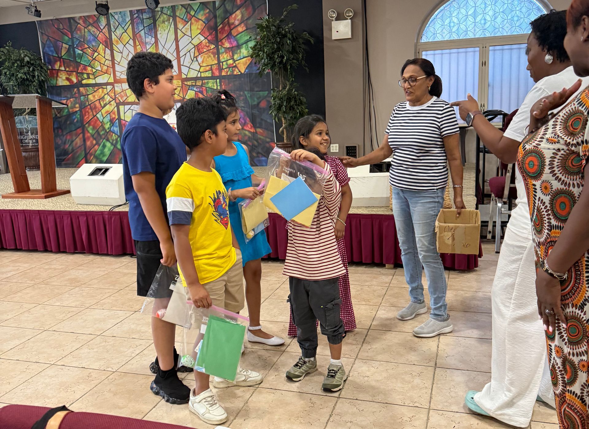 Children standing and talking with an adult in a colorful indoor hall