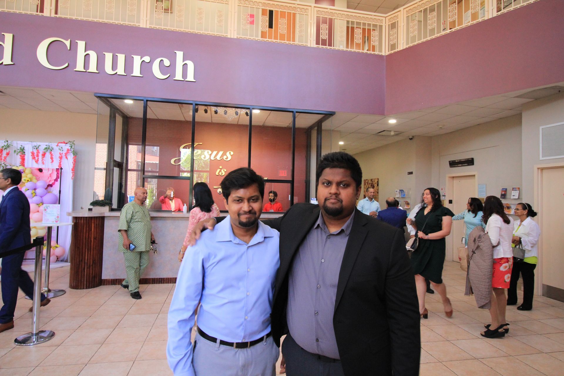 two men are posing for a picture in front of a church