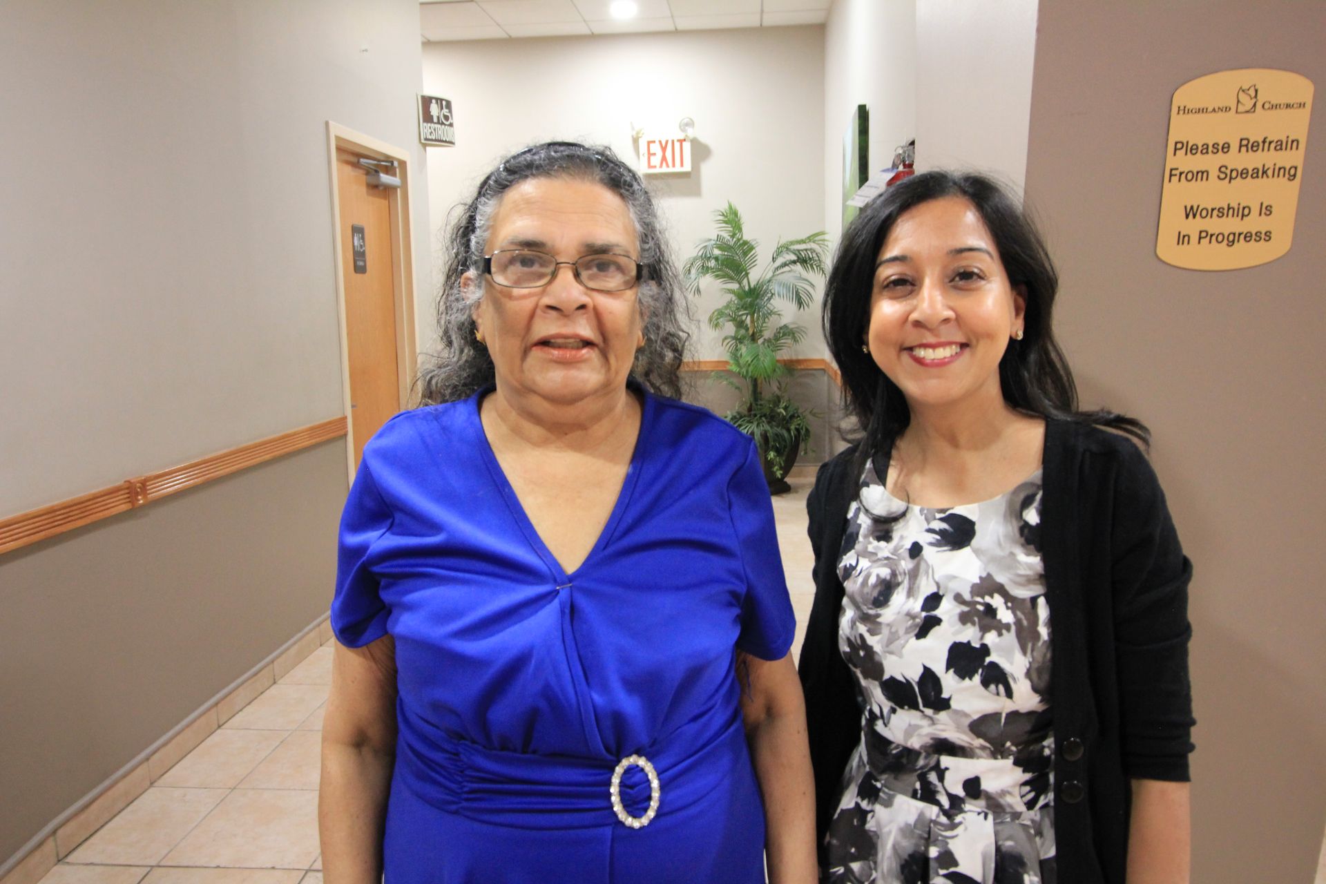 two women are standing next to each other in a hallway in front of a sign that says staff
