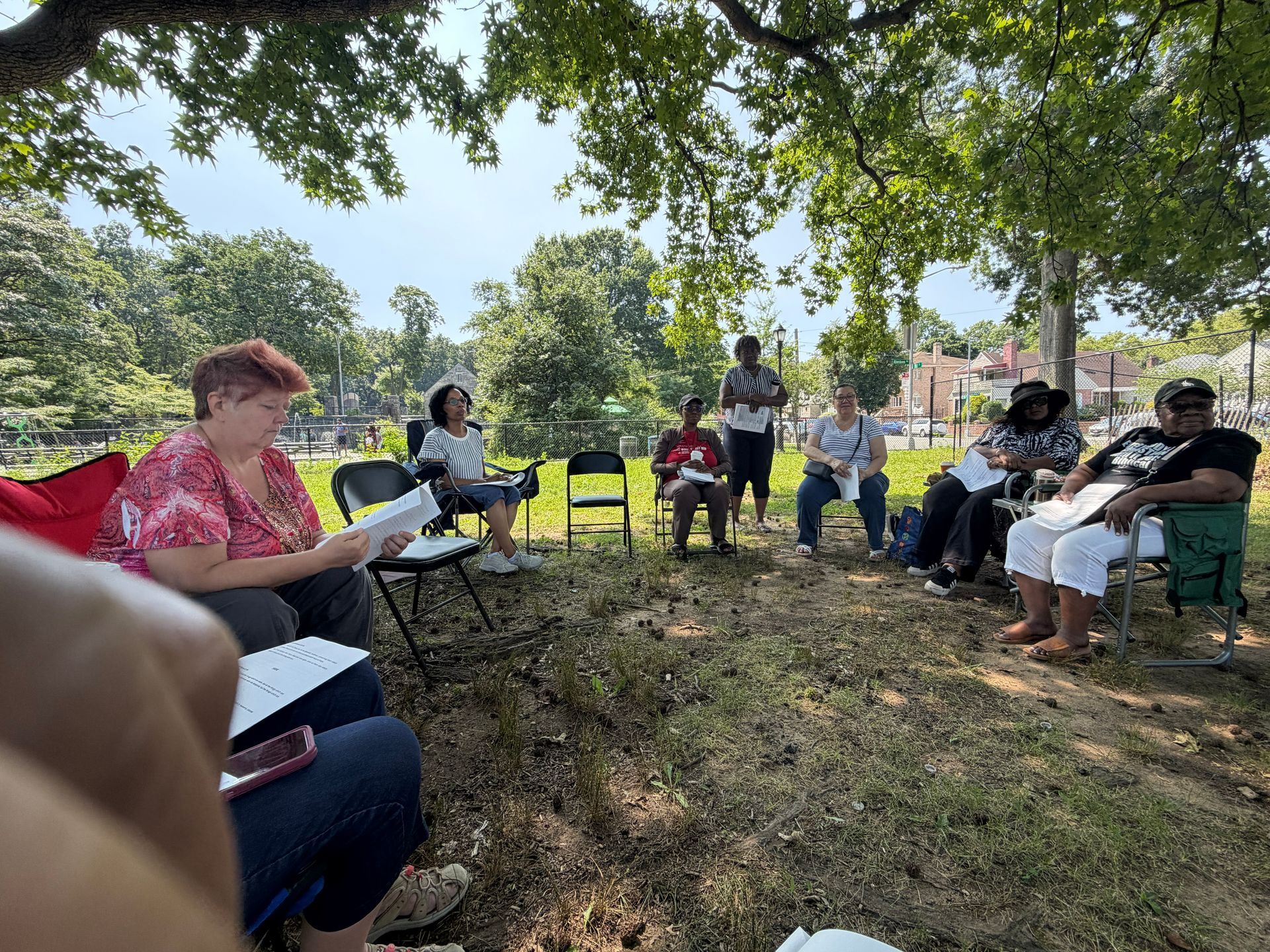 People seated in a shaded outdoor circle during a group discussion under trees