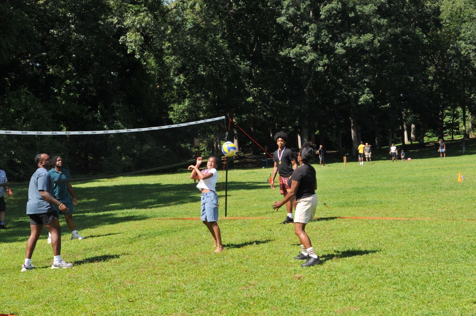 People playing volleyball on a sunny grassy field in a park