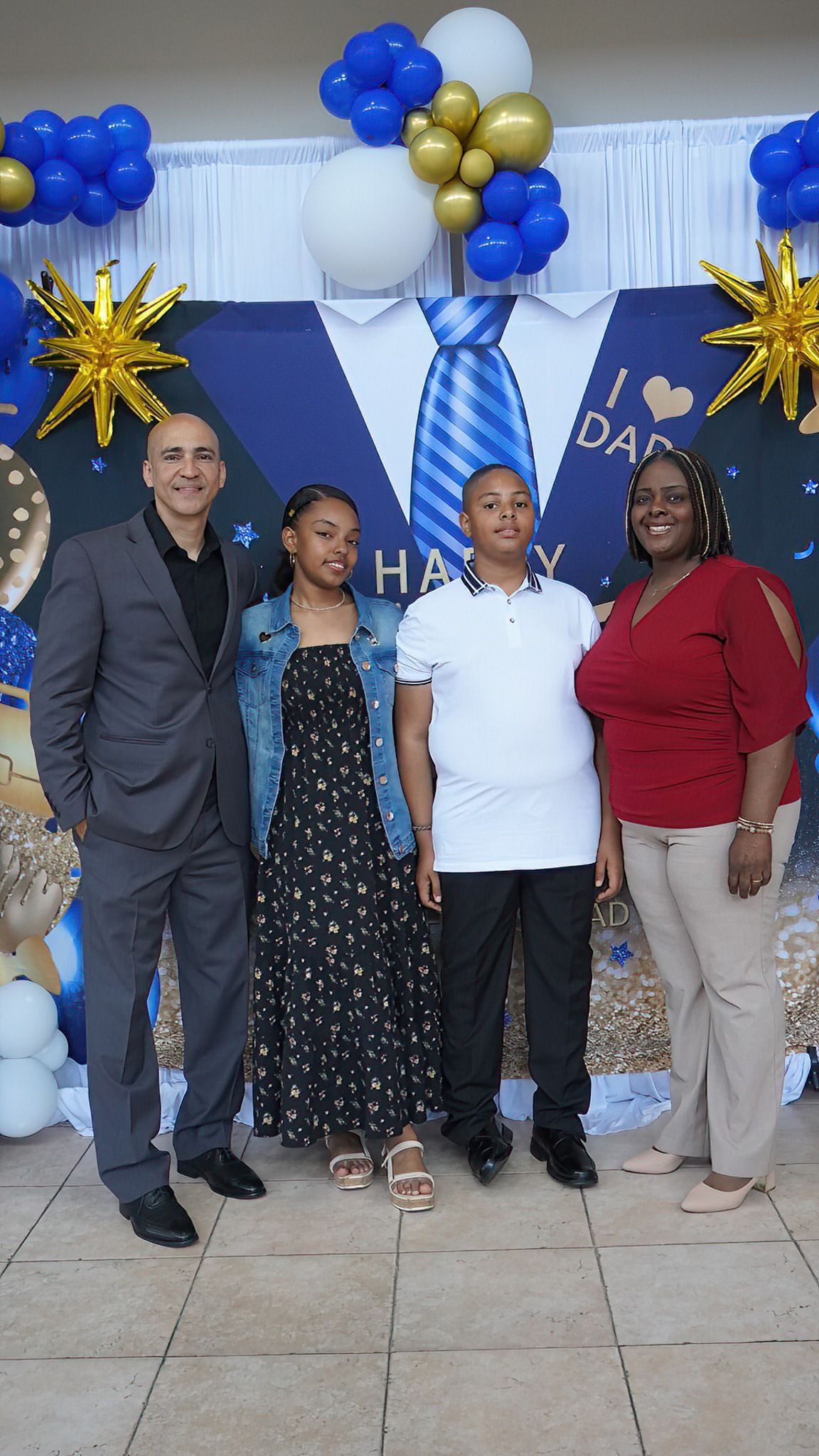 A group of people are posing for a picture in front of a wall decorated with balloons.