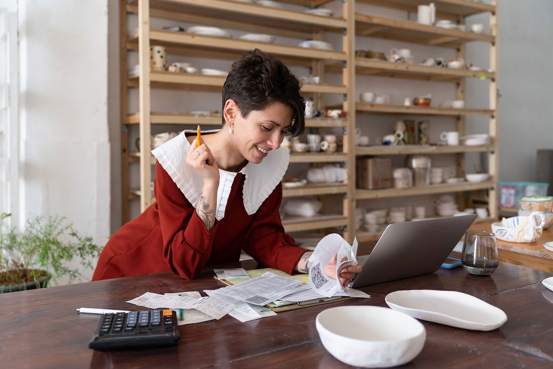 Bookkeeping in small business. Satisfied successful businesswoman ceramic studio owner calculating revenue, paying bills or taxes online, analyzing material costs to produce pottery. Entrepreneurship
