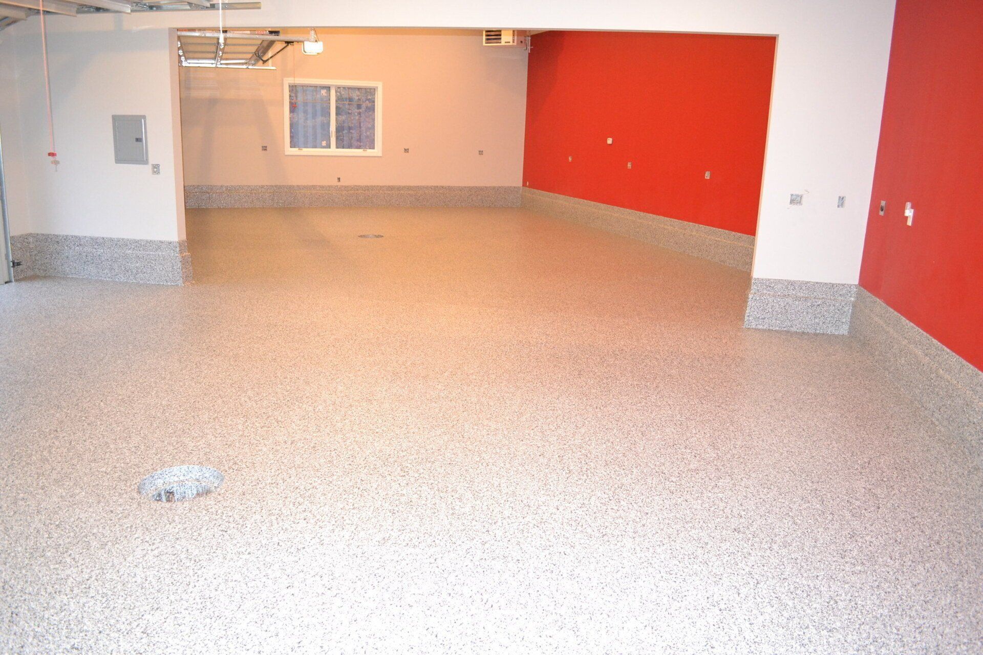 Light tan flake floor in a large garage with a red accent wall