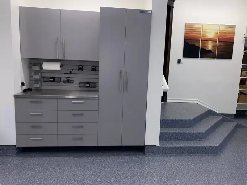 Custom gray powder-coated garage storage cabinets with stainless countertop and slatwall