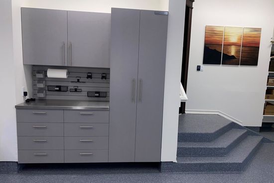 Gray garage cabinets with a stainless counter beside coated steps