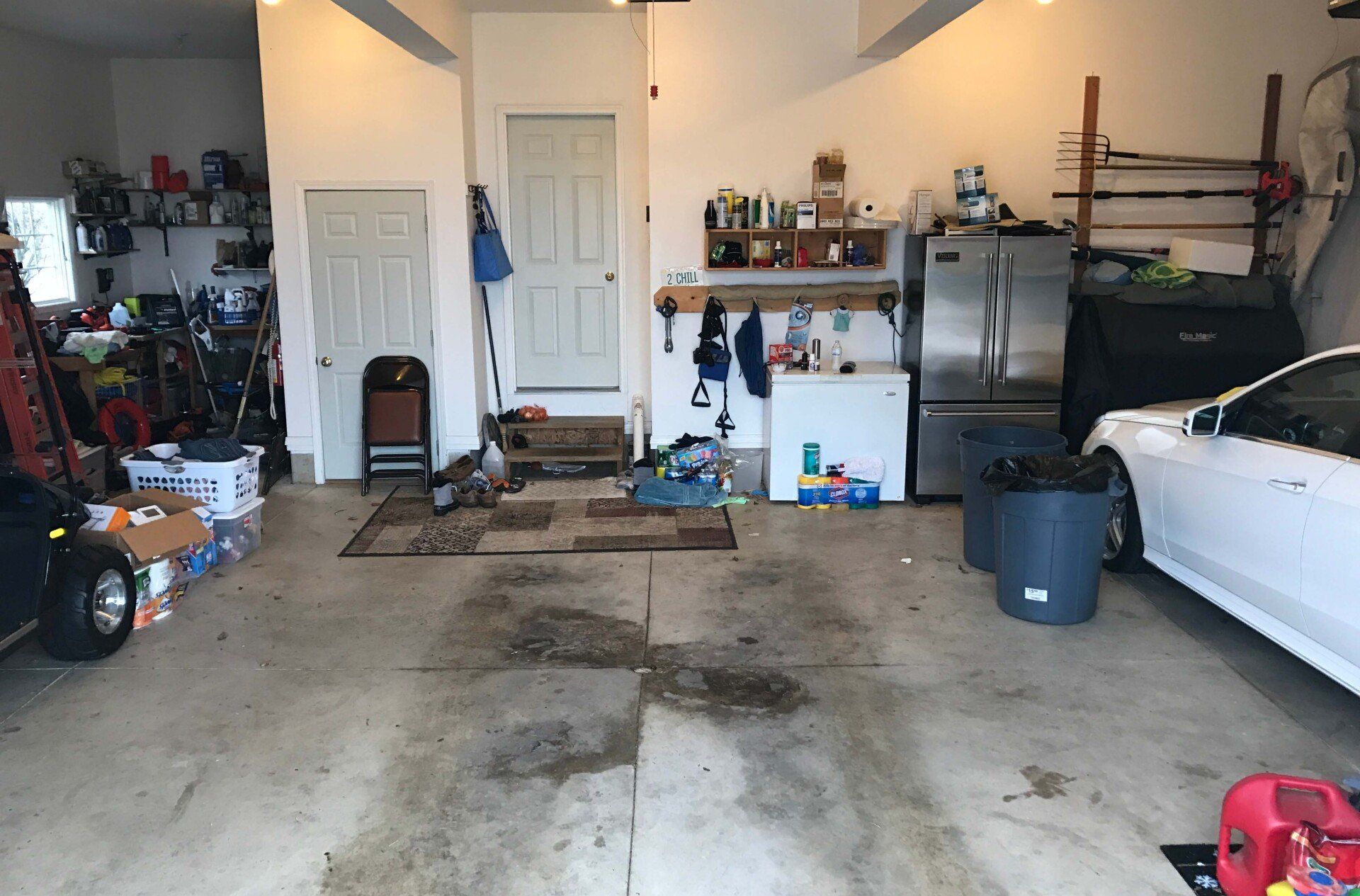 Before: cluttered two-car garage with a stained concrete floor