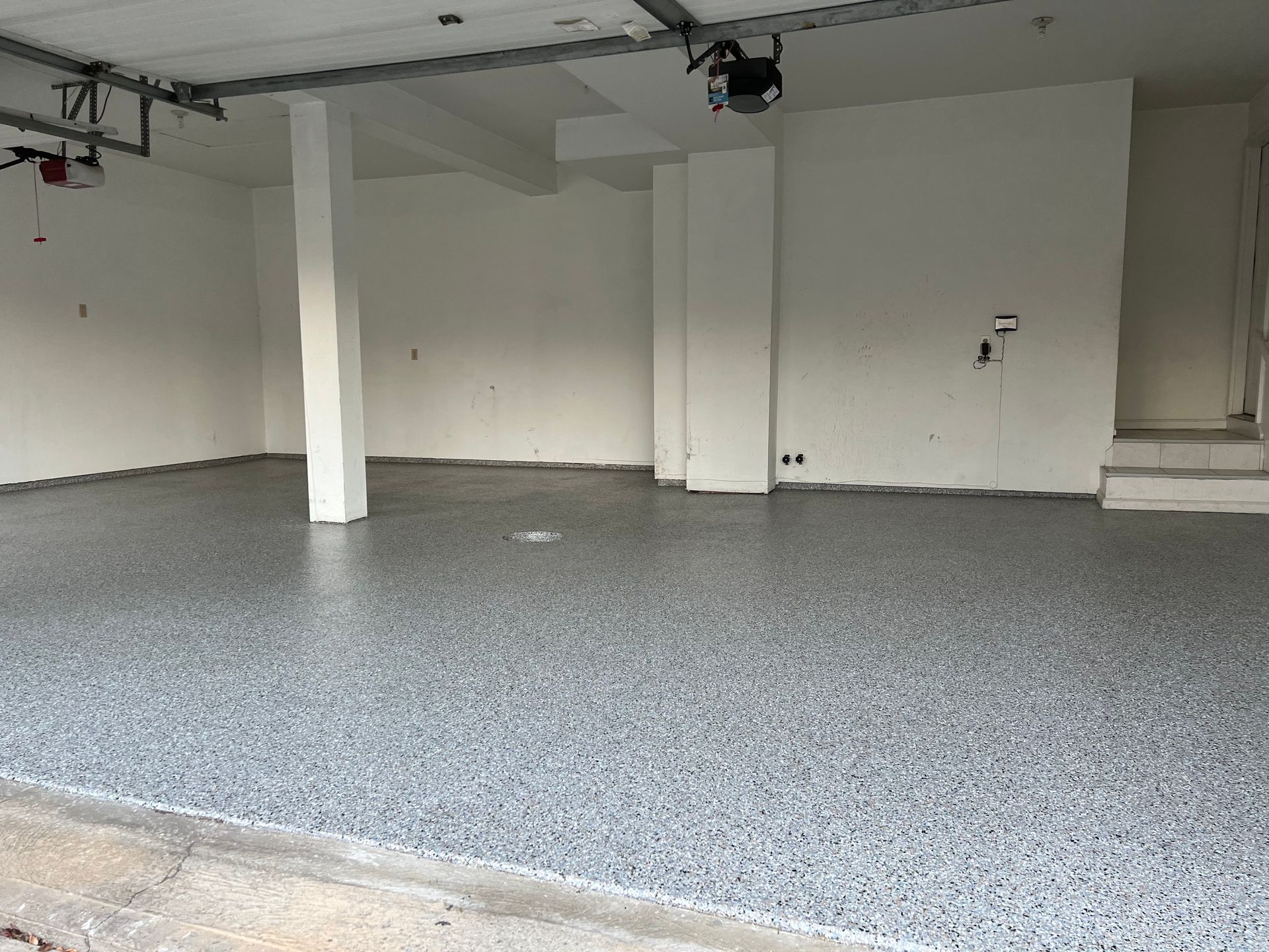 Gray flake polyaspartic floor in an empty two-car garage