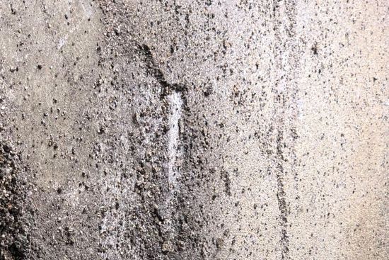 Close-up of a worn, pitted Nature Stone garage floor surface