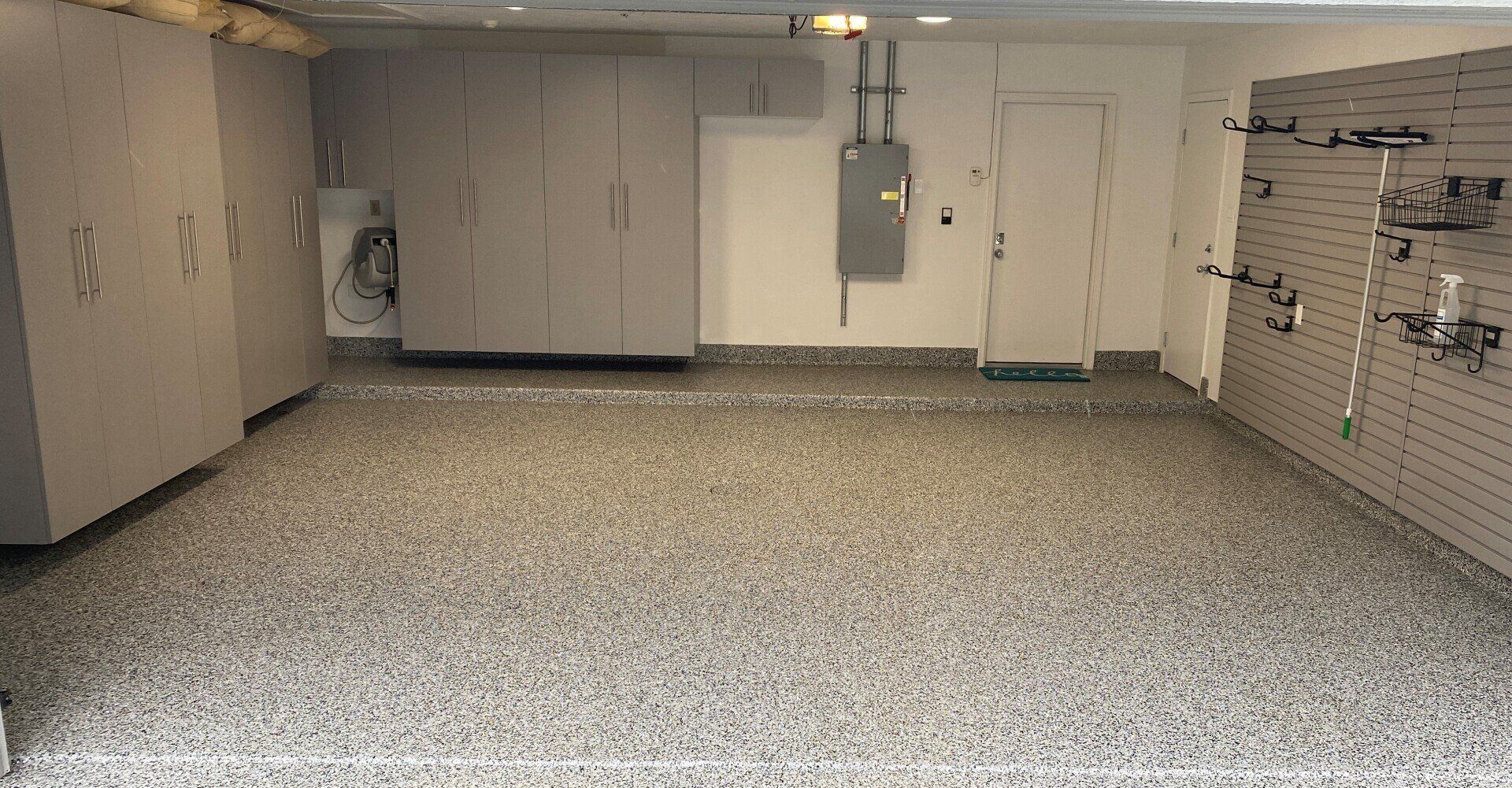 Gray flake garage floor with gray cabinets and a slatwall