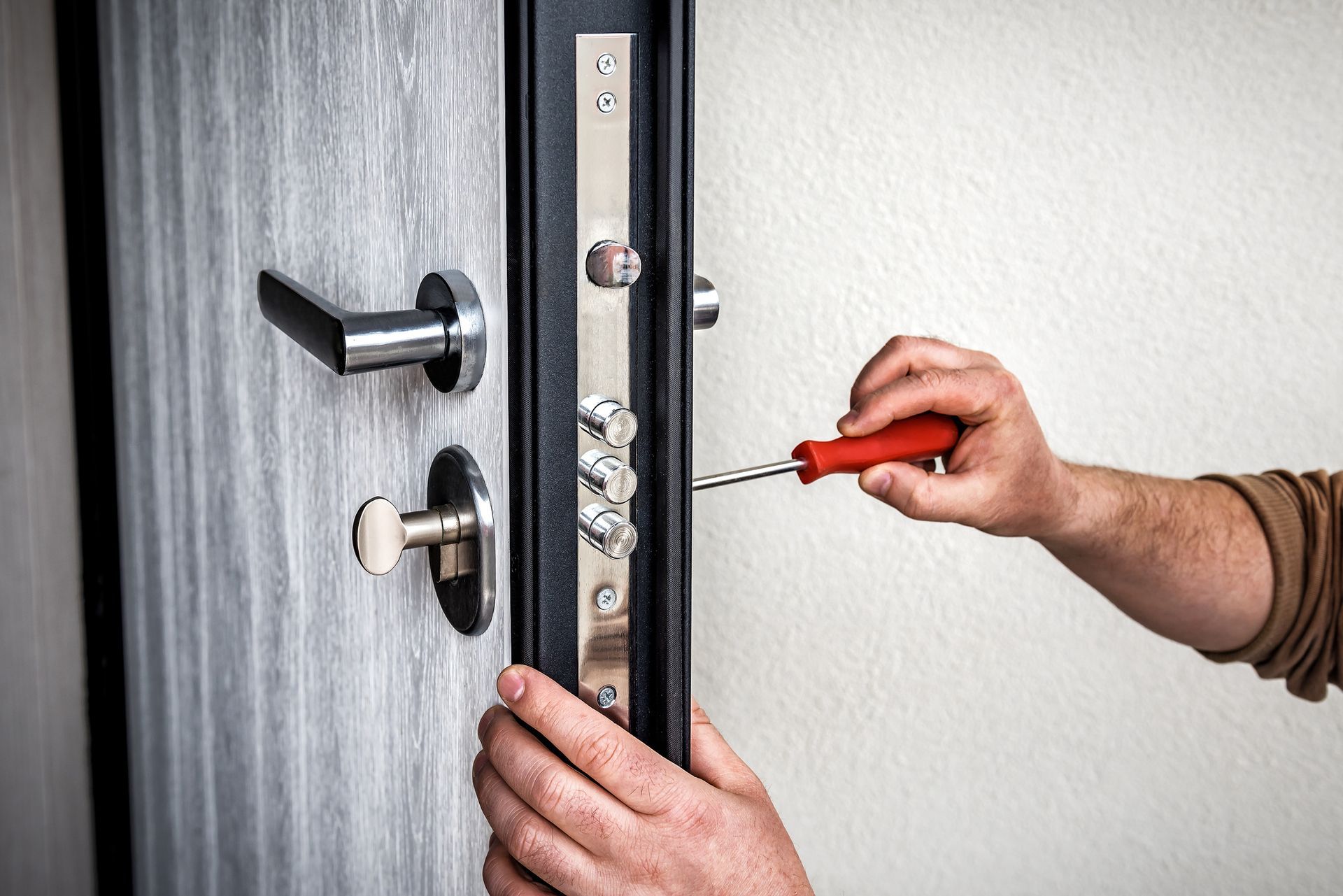 A person is fixing a door with a screwdriver.