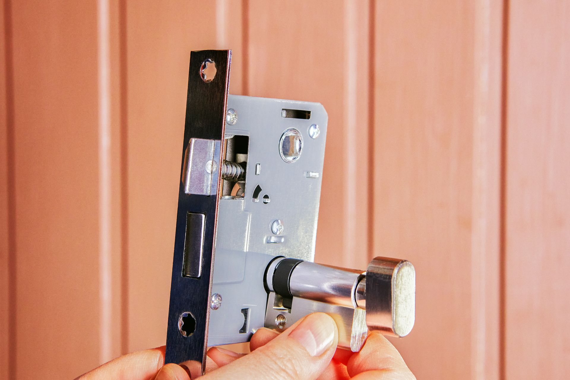 A person is holding a door lock in their hands.