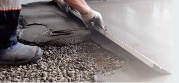 Worker Smoothing Wet Concrete With a Trowel Beside a Curb — Outdoor Concreting in Townsville, QLD
