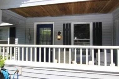 Front porch with a white railing and gray siding. 