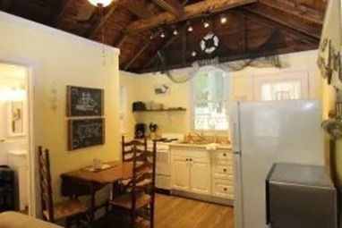 Small kitchen with a refrigerator, cabinets, table, and decorative fishing net.