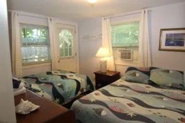 Bedroom with two beds, window, and a door.