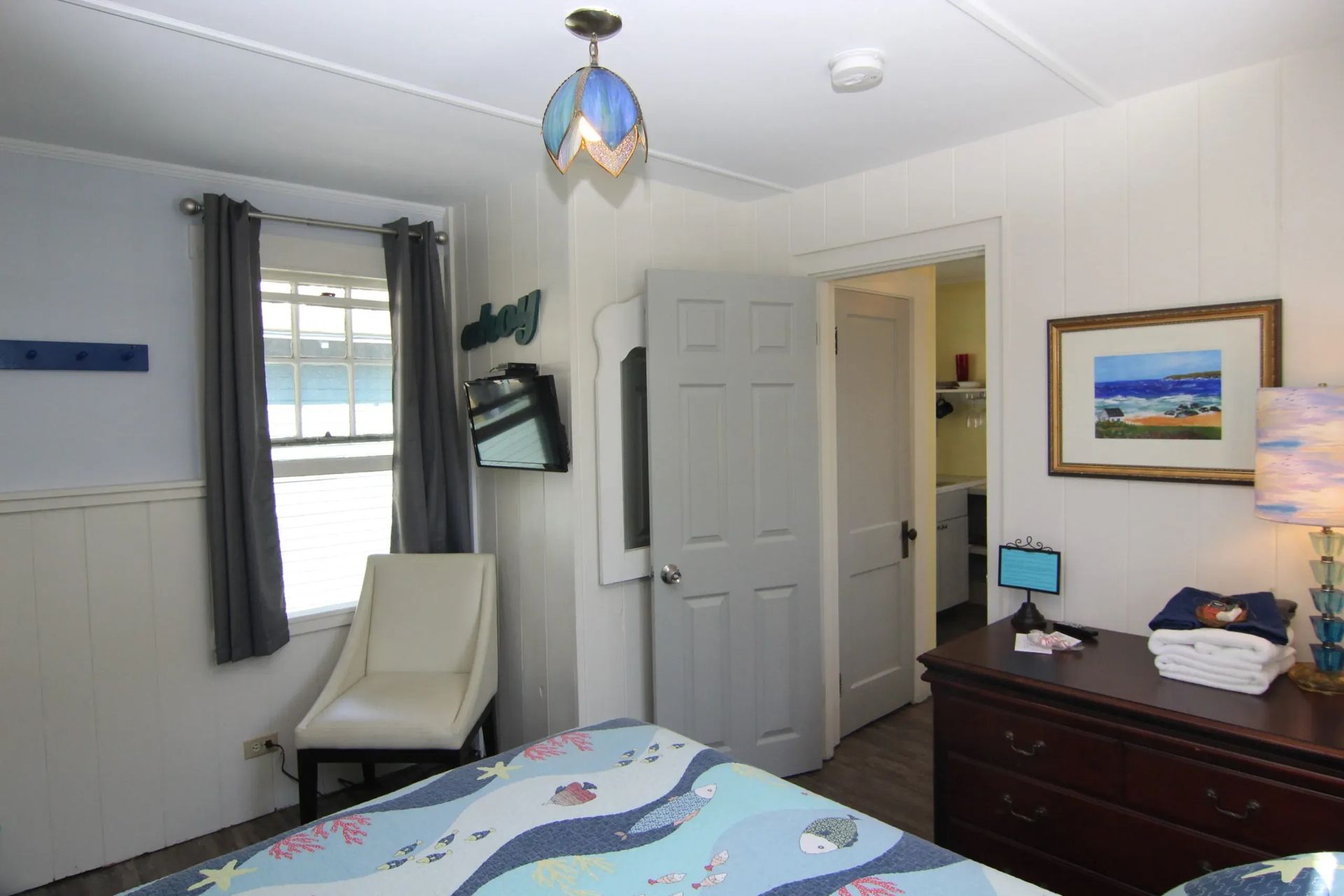 Bedroom with bed, chair, window, dresser, open door to another room.