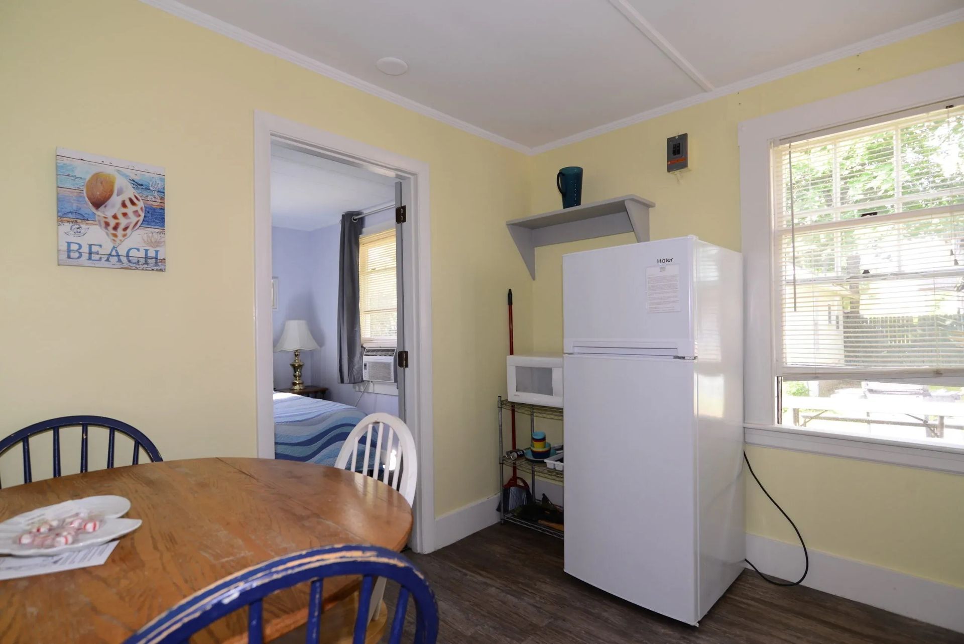 A small kitchen area with a table, chairs, fridge, and microwave.