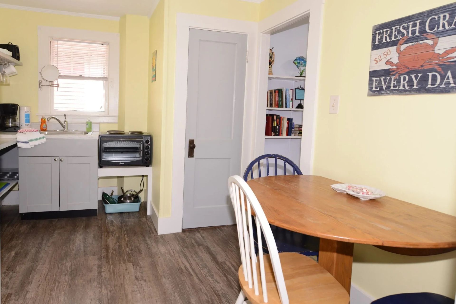 Kitchen with yellow walls, gray cabinets, and a wooden table. 