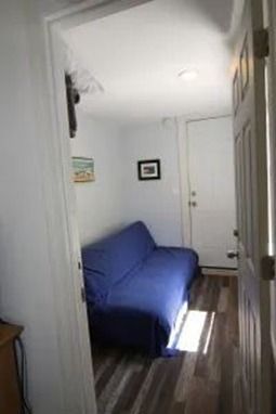 Narrow hallway with a blue futon and a white door.