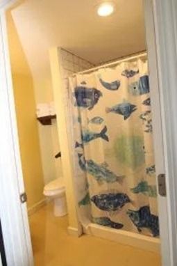 Bathroom with toilet and shower curtain featuring blue fish designs.