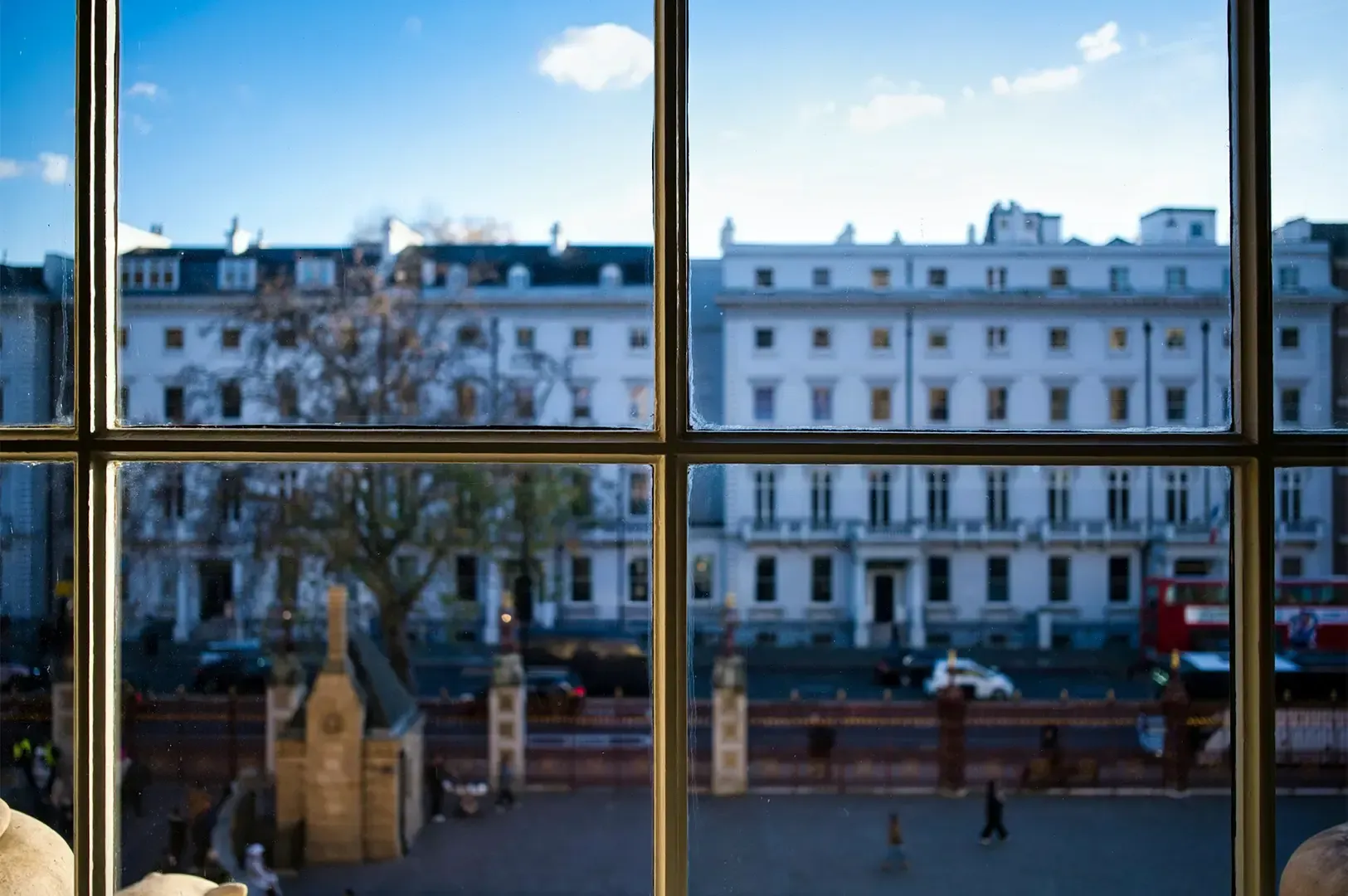 Wide angle shot of two white buildings side by side one another beside a busy street full of passing
