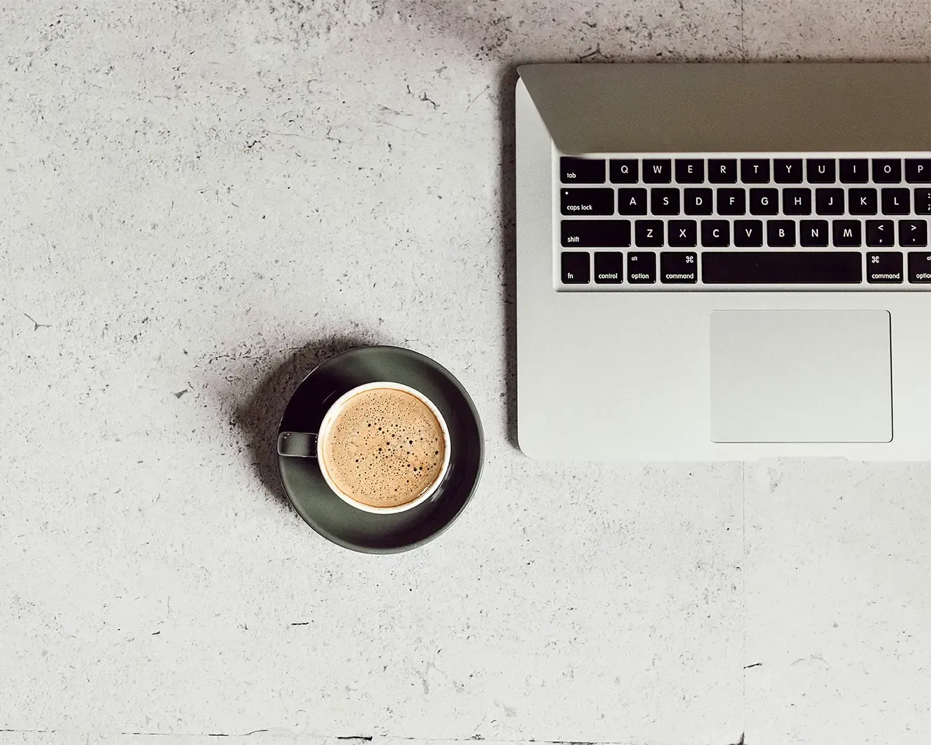 A laptop placed on a clean table beside a cup of coffee, creating a calm and focused workspace. The scene suggests a quiet moment of productivity.