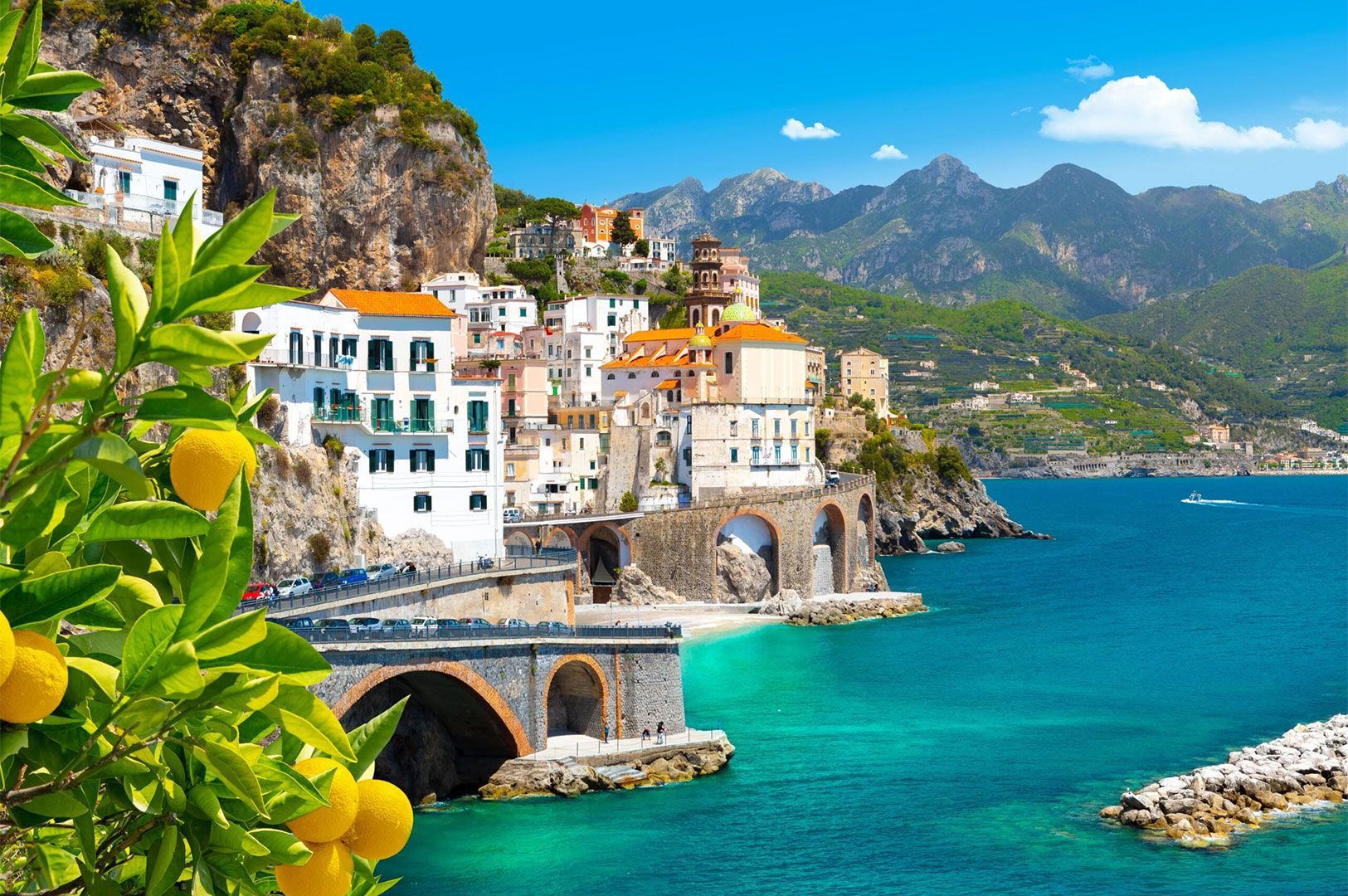 Panoramic view of the colorful houses and architecture of an Amalfi Coast town, with a lemon branch 