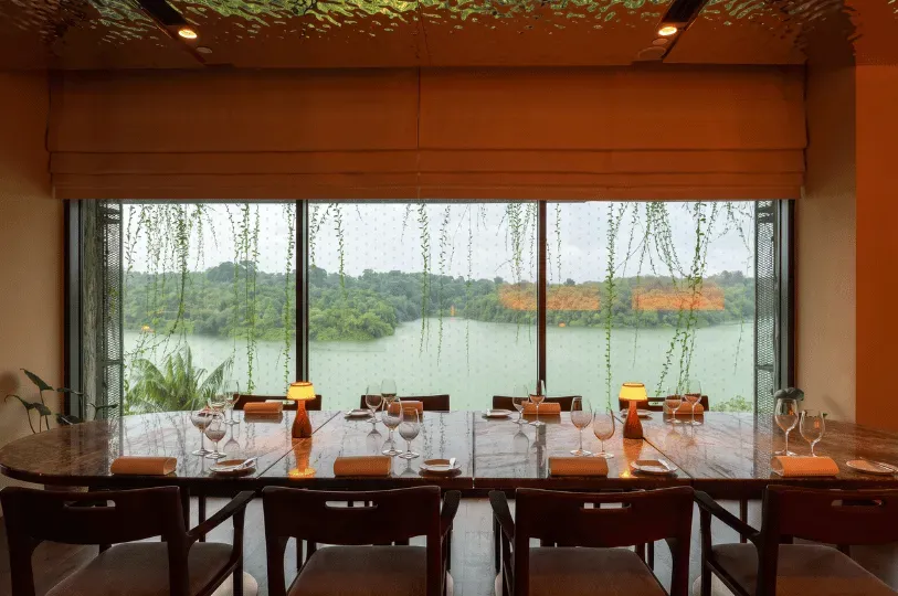 A serene dining room featuring a long marble table set for a meal, surrounded by dark wooden chairs.