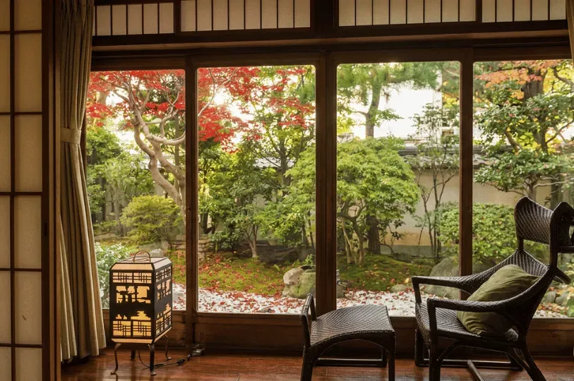 A tranquil view from inside a room looking out through large sliding glass doors into a serene Japan