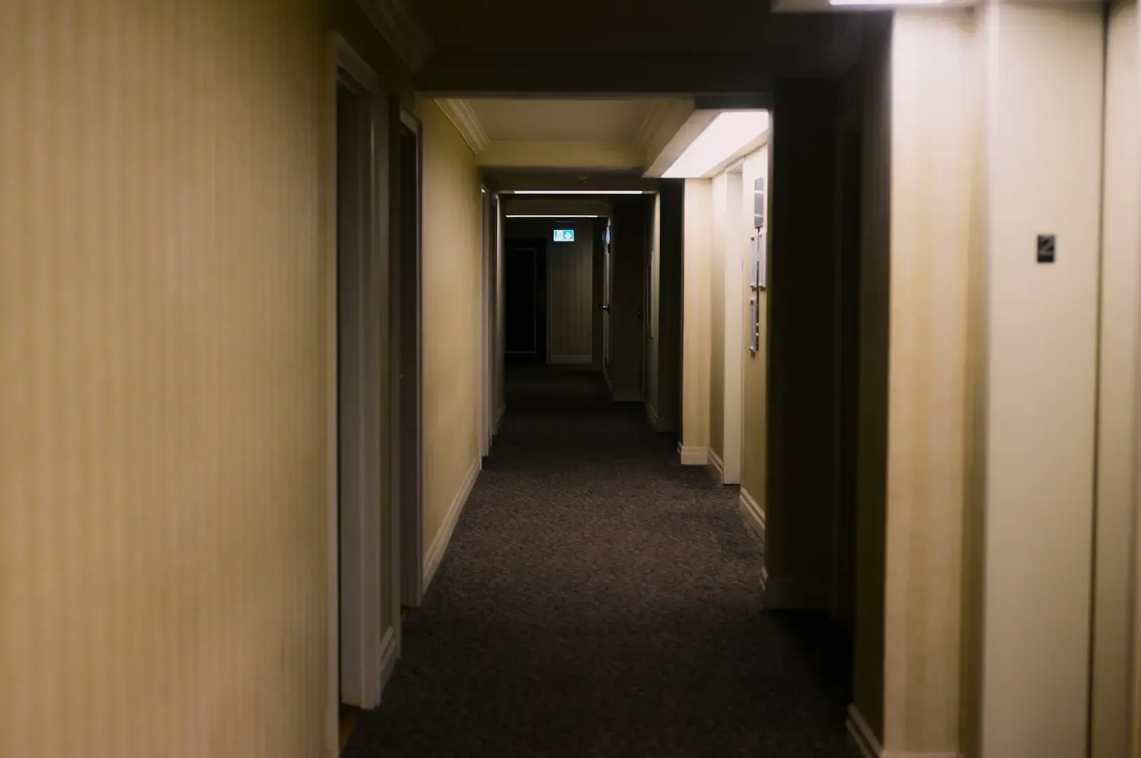 A dimly lit hotel corridor with simple wall and floor designs.