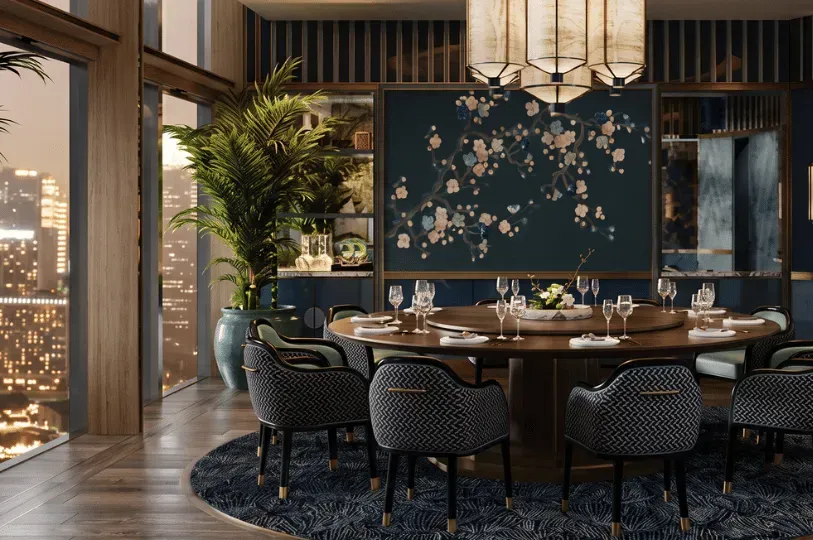 A sophisticated private dining room centered around a large round wooden table and patterned upholstered chairs. The space is elegantly decorated with a dark blue wall featuring a floral blossom mural, an illuminated chandelier, and floor-to-ceiling windows revealing a city skyline at twilight.