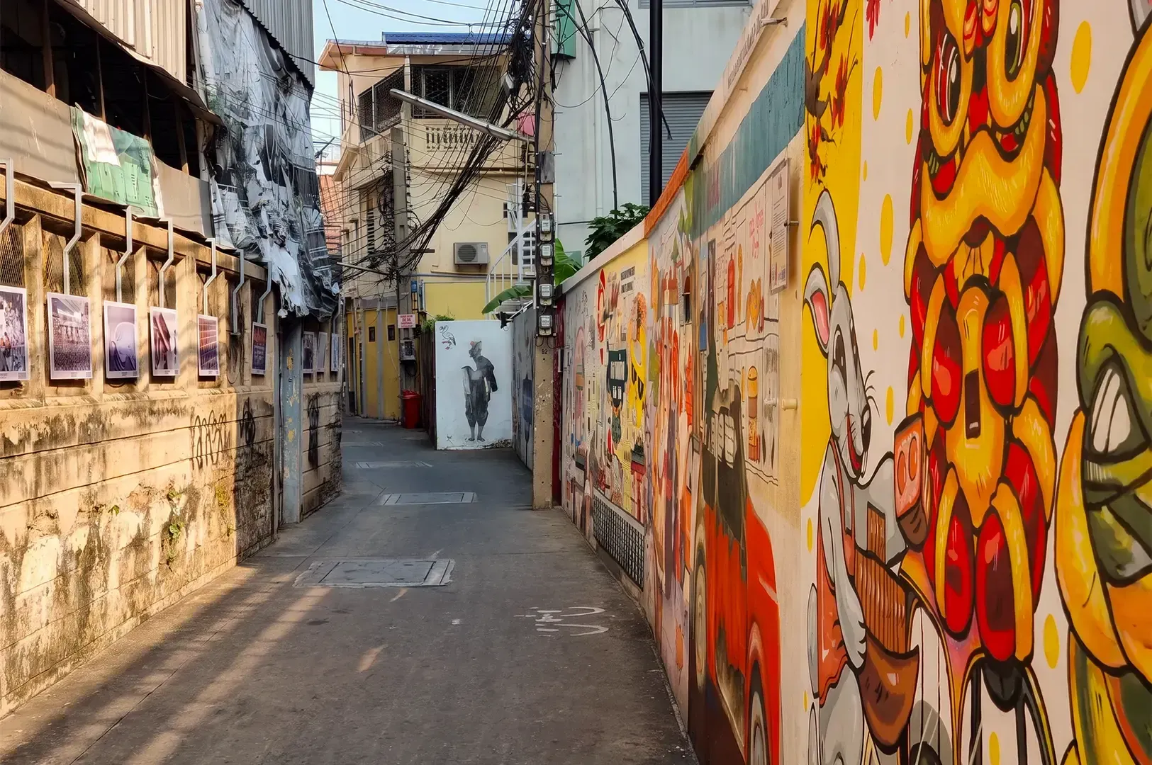A narrow street in Talat Noi with graffiti on the right wall and buildings on either side.