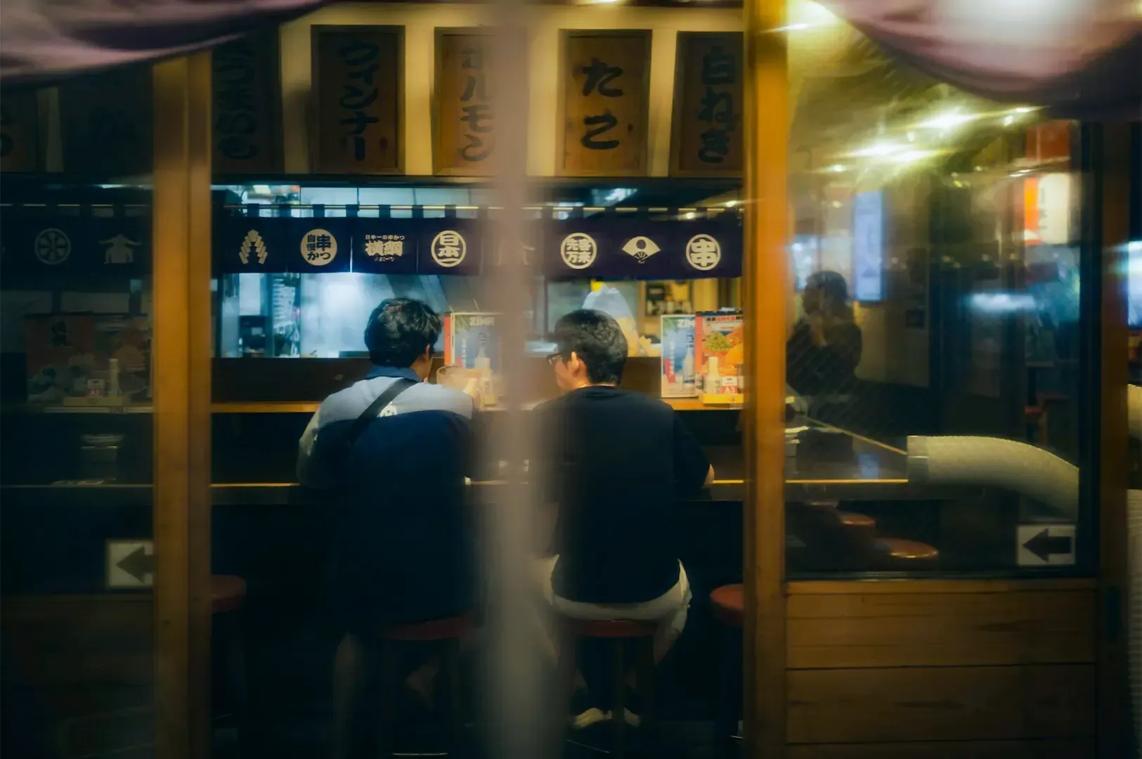 Two people side by side each other casually talking by an Asian style counter.