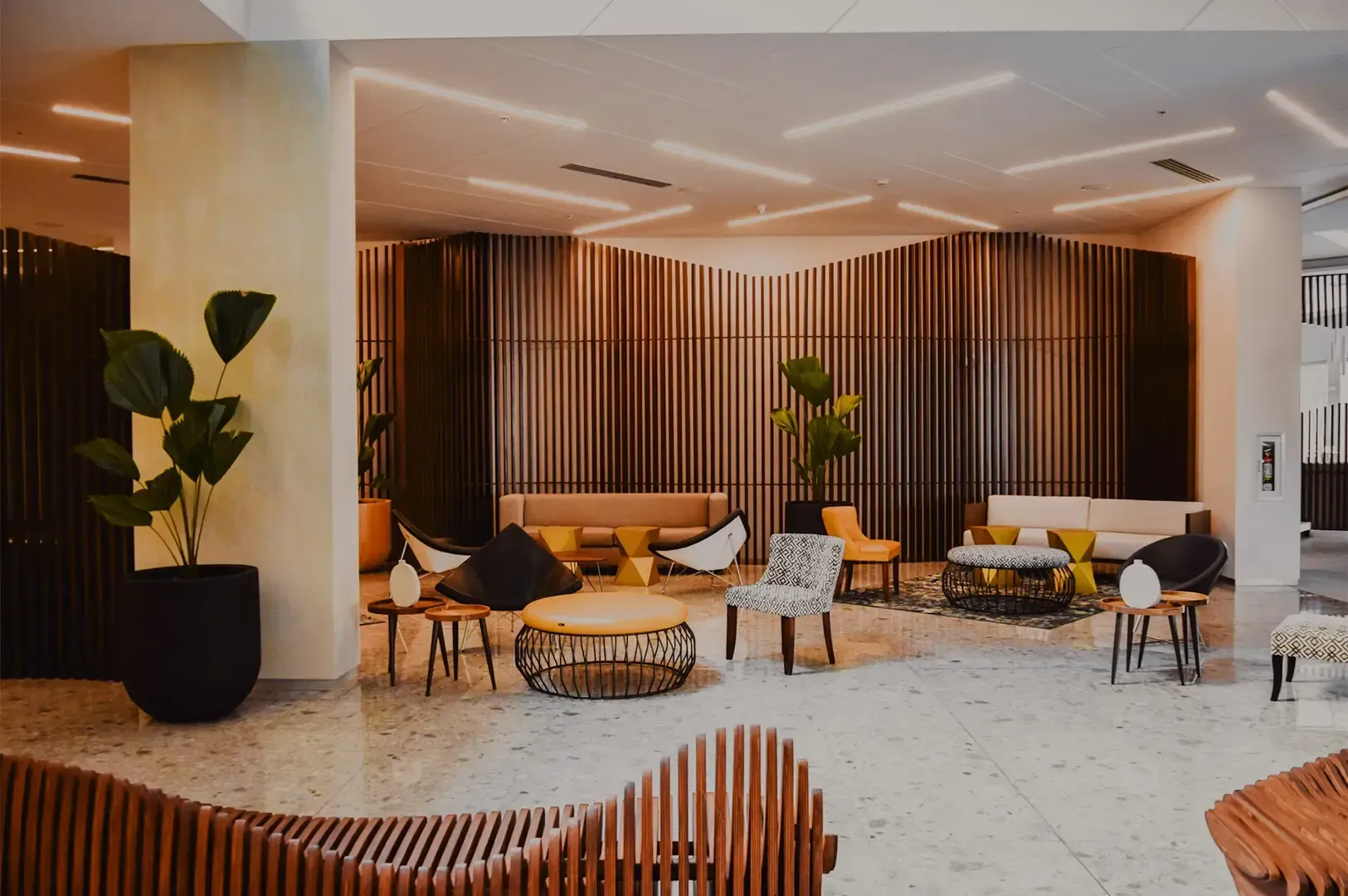 An empty and peaceful hotel lobby illuminated by cozy warm lights with tables, chairs, and couches around.