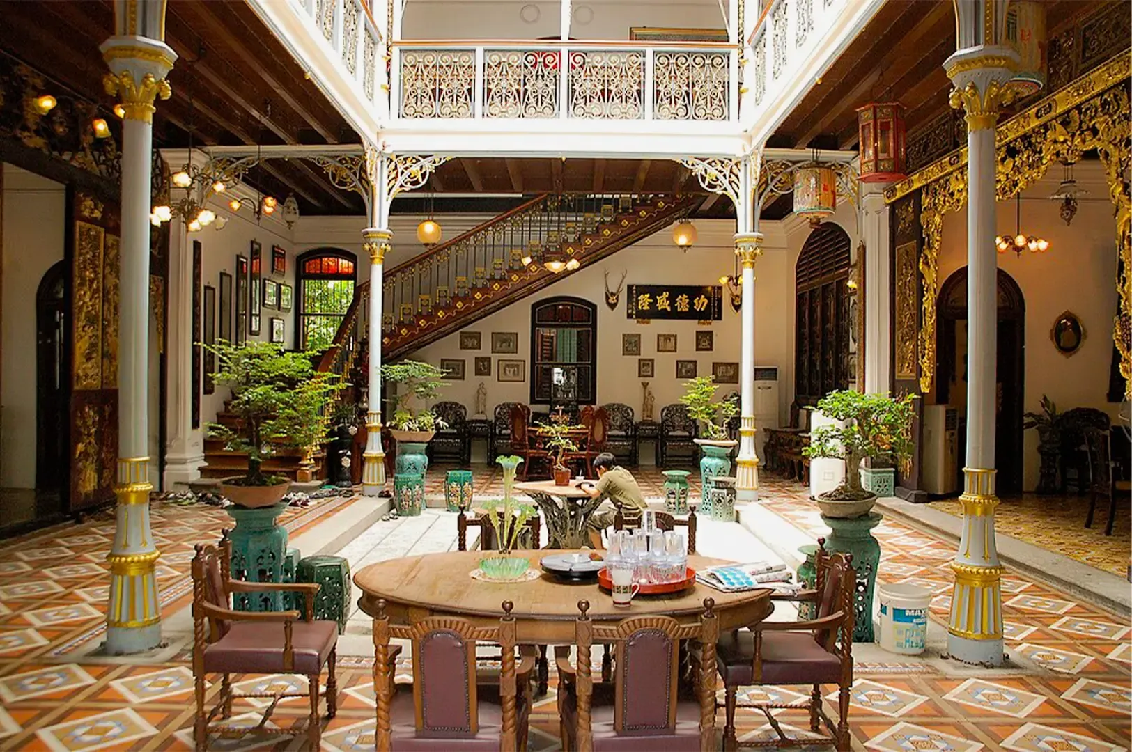 Pinang Peranakan Mansion interior located in George Town, Penang with luxurious furniture in the center and a white and gold themed pillars and accents.