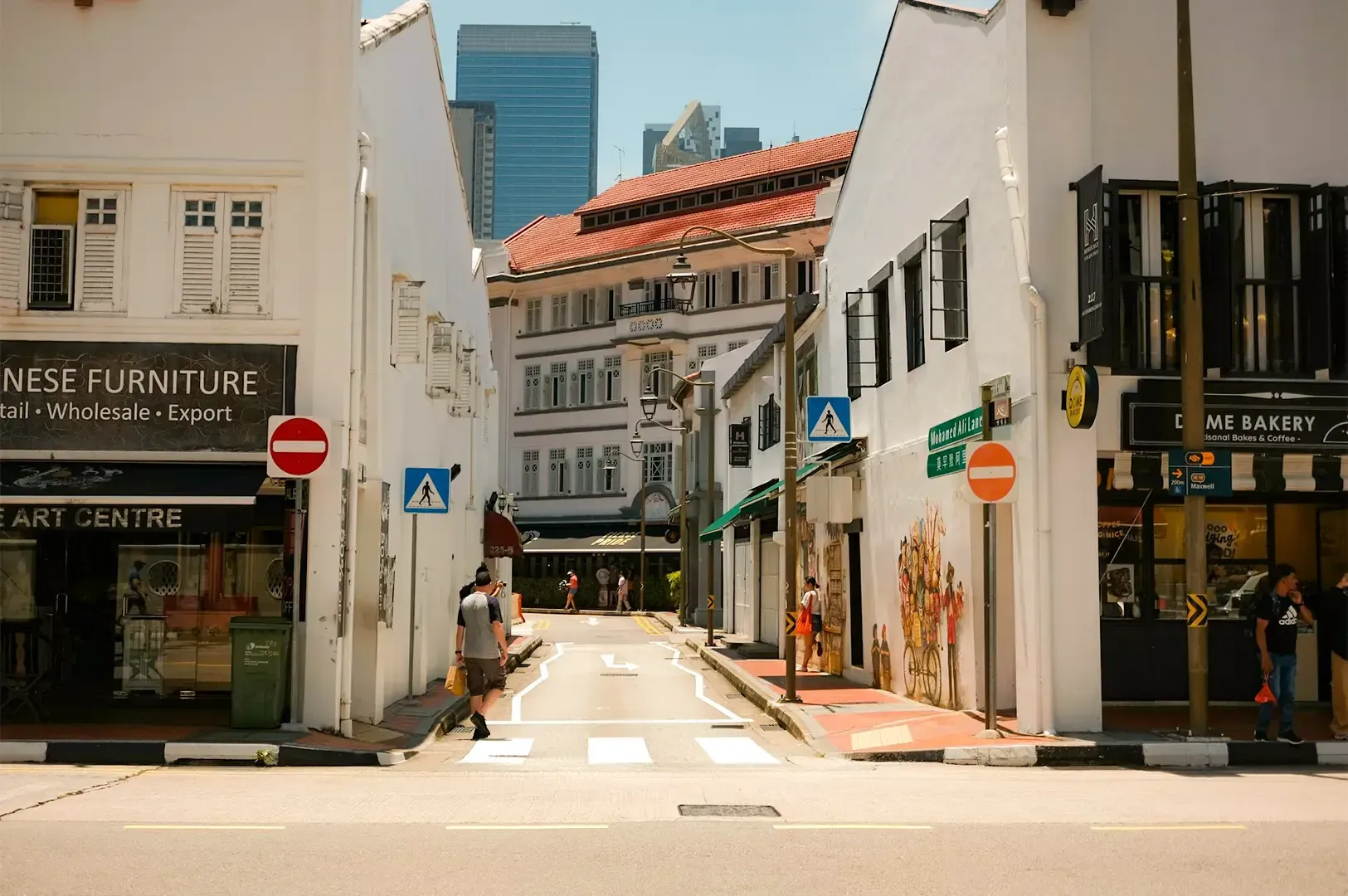 A street between two white buildings with a person walking along the left side.