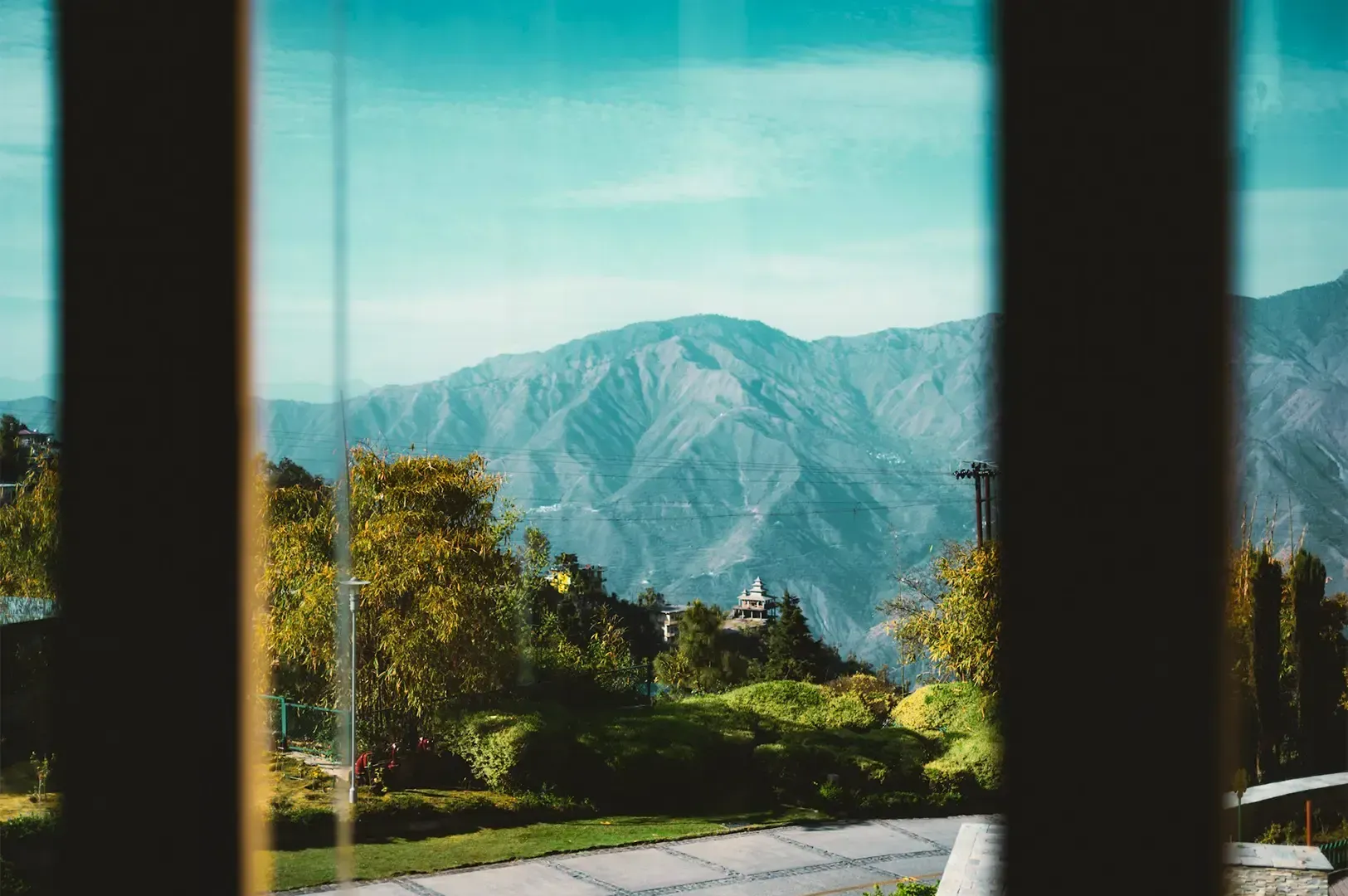 A scenic nature view of a mountain and trees viewed from a window.