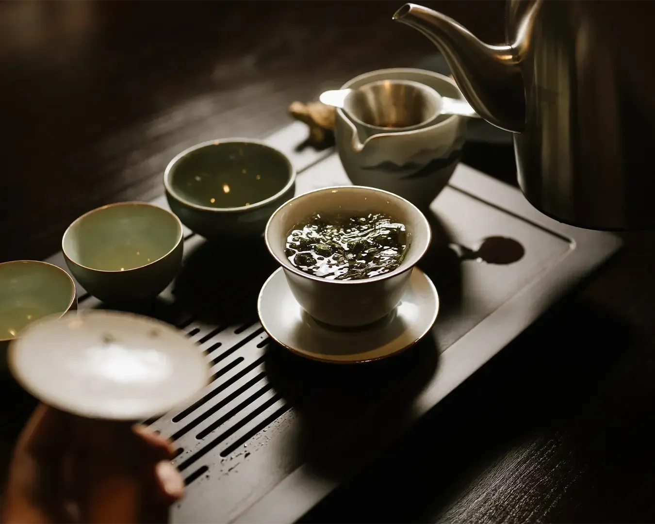 A Chinese cup of tea with loose tea leaves resting at the bottom, highlighting the natural brewing process and the rich colour of freshly steeped tea.