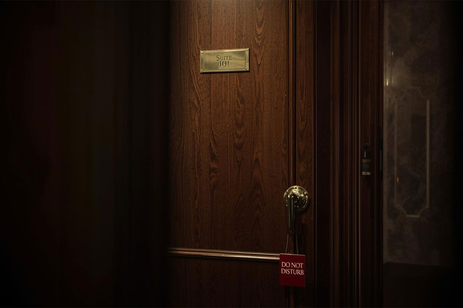 Close-up of a luxurious dark wood hotel door with a brass plaque reading