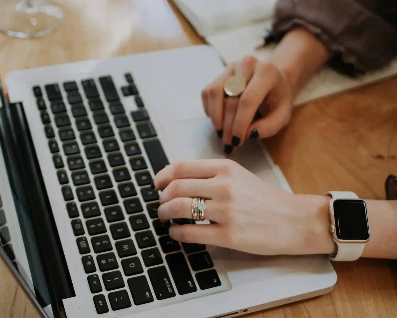 Hands actively typing on a laptop keyboard, focused on completing digital work. The scene highlights productivity, remote work, and modern communication as fingers move quickly across the keys in a workspace setting.