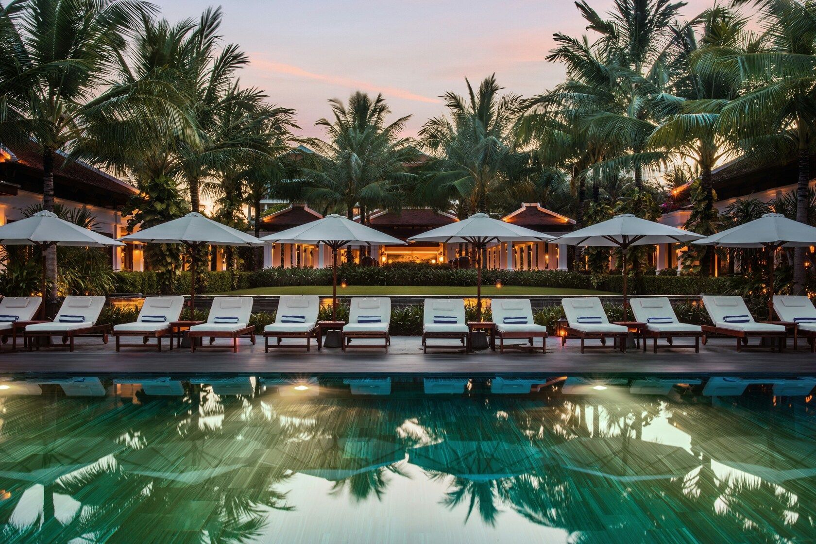 Travelling Assistant : A serene hotel pool surrounded by tropical greenery, perfect for relaxation.