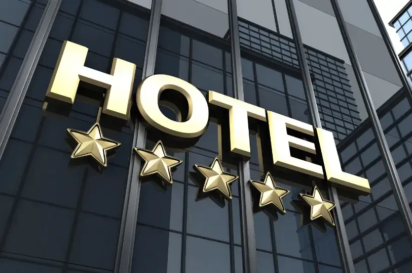 A uniformed hotel bellhop pushes a classic brass luggage cart loaded with bags through a luxurious.