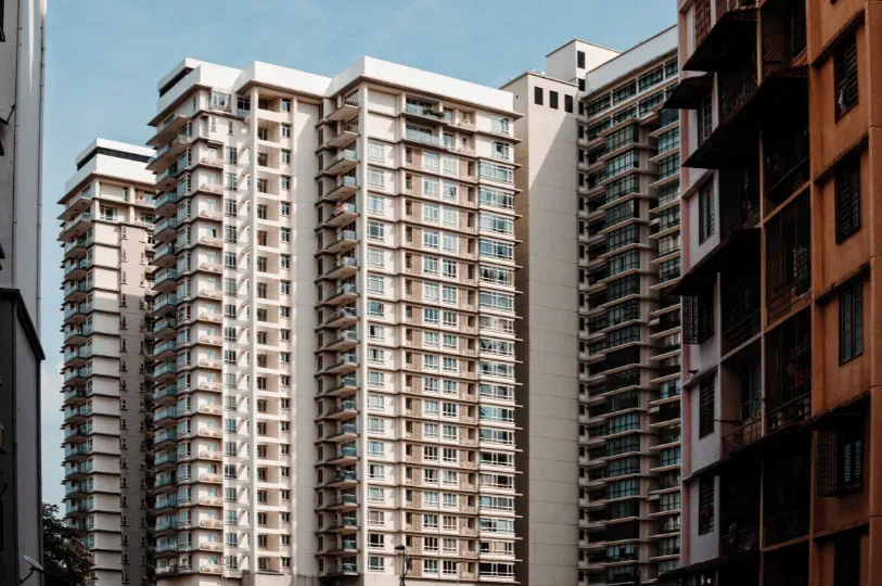 A dense cluster of towering, multi-story residential apartment buildings in Kuala Lumpur, showcasing the repeating patterns of balconies and high-density urban living.