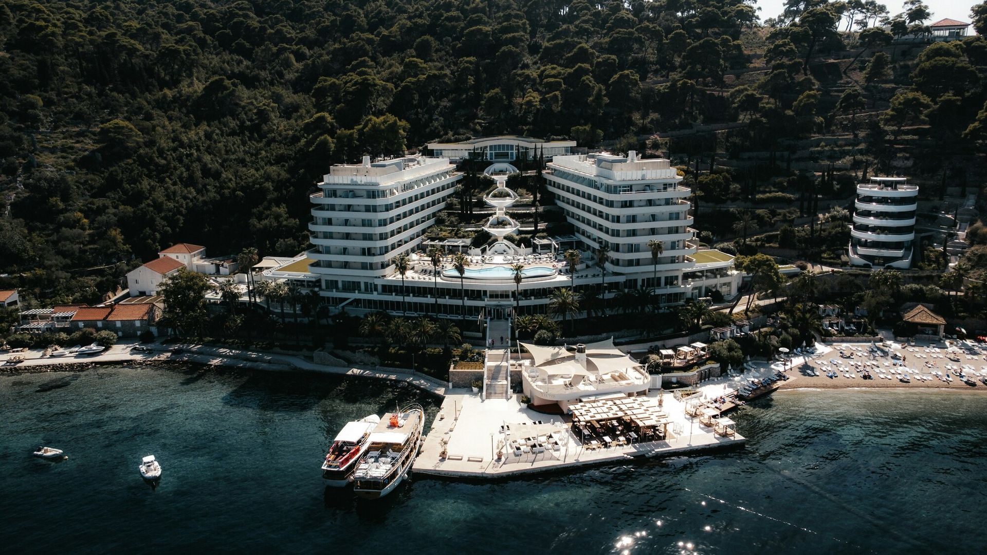 5 Ultra-Luxury Hotels: Panoramic drone shot of a high-end island resort blending seamlessly with nature.