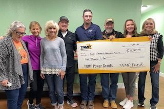 A group of people standing next to each other holding a large check.