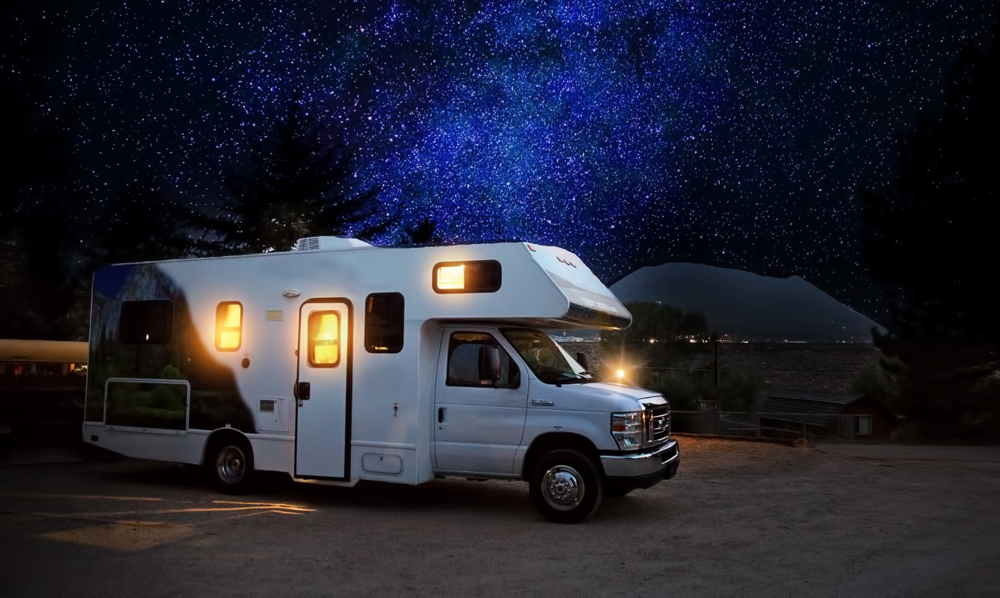 A white rv is parked under a starry night sky.